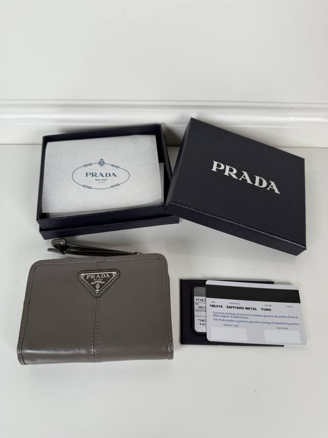 P is a short wallet made of gray oiled waxed cowhide, model number 1Ml018. It ha