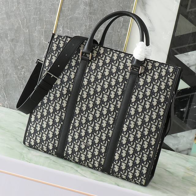 This East-West bag embodies timeless elegance. Crafted from beige and black Obli
