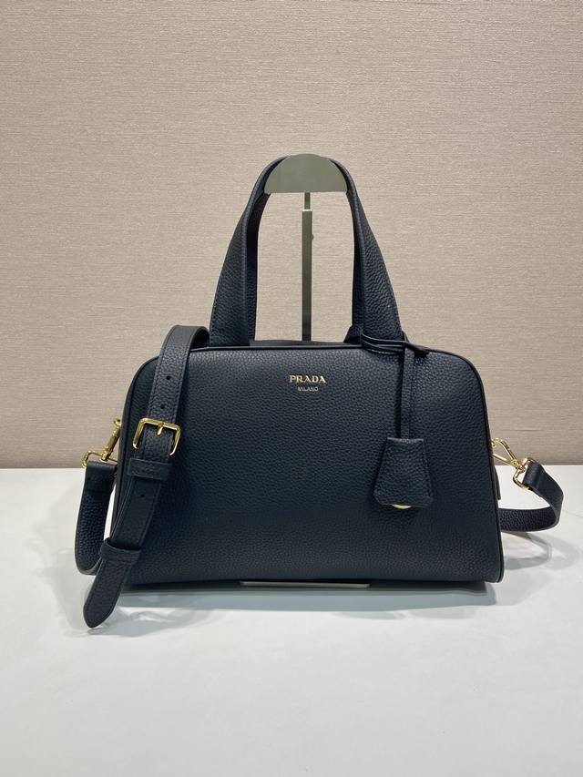 新品1Bb148 这款天然粒面皮革制成的顶部提手包袋以柔软的轮廓进行了重新诠释，可手提或搭配可拆式肩带佩戴，配有2个可拆卸吊牌。金属硬件。正面带有浮雕字母标志，