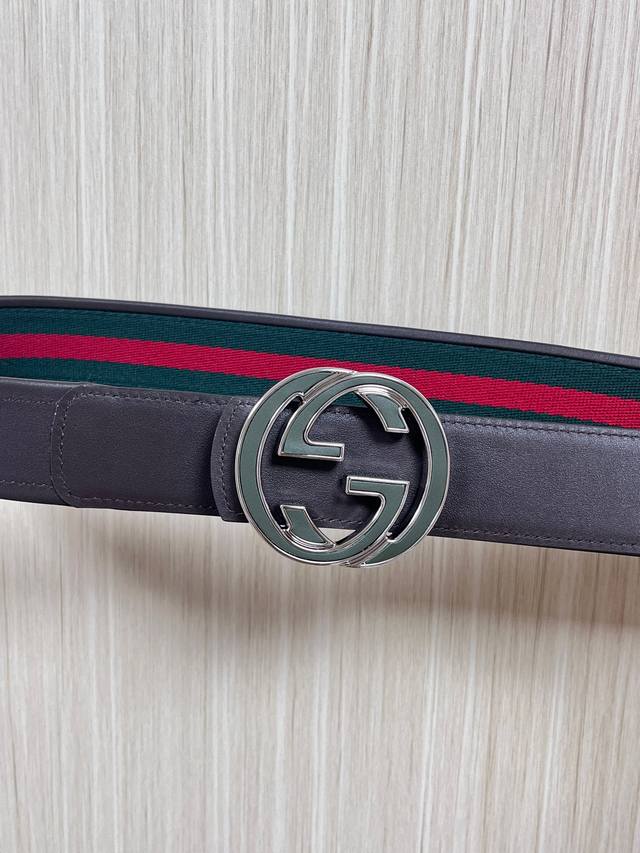 This reversible belt features red and green webbing and dark brown cowhide leath