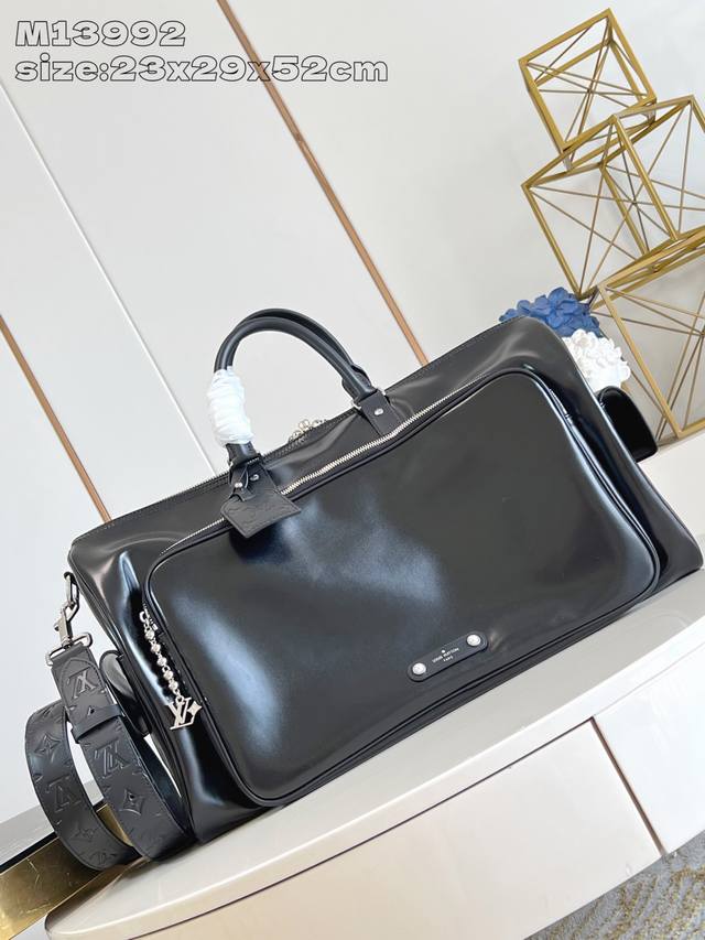 M13992 本款 Keepall Cargo BandoulièRe 50 旅行袋为亮面牛皮革浸染深邃色调，令经典设计在动静间捕捉光影变幻，展现 pharre