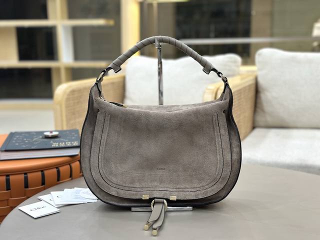 Chloe 2026麂皮包 Chloe 2026系列进口高丝光麂皮包，柔软麂皮材质+黑色皮革边饰，简约又有质感。弧形包身+金属扣件，细节满分！顶部手柄可手提或肩