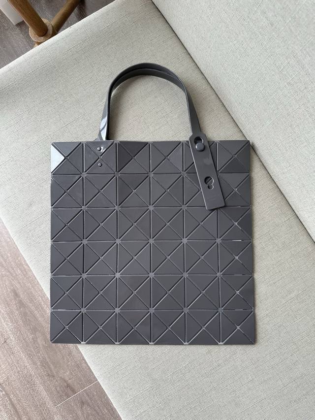 三宅一生 五月新品 六格亮面同色系列--深灰lucent系列托特包采用具有光泽的漆面材料制成。通过使用与三角珠片相同颜色的纱线织就而成的网眼面料与衬里，打造出一
