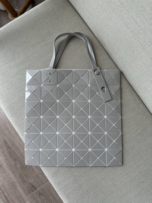 三宅一生 五月新品 六格亮面同色系列--浅灰色lucent系列托特包采用具有光泽的漆面材料制成。通过使用与三角珠片相同颜色的纱线织就而成的网眼面料与衬里，打造出