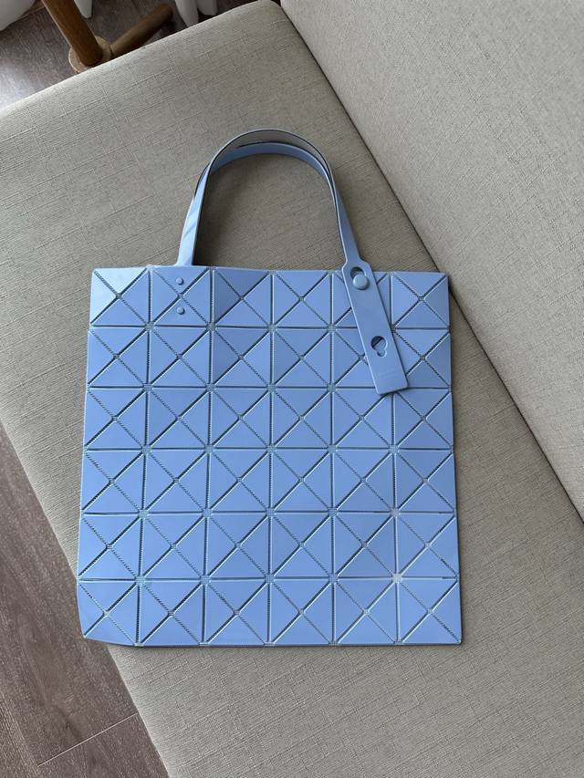 三宅一生 五月新品 六格亮面同色系列--浅蓝lucent系列托特包采用具有光泽的漆面材料制成。通过使用与三角珠片相同颜色的纱线织就而成的网眼面料与衬里，打造出一