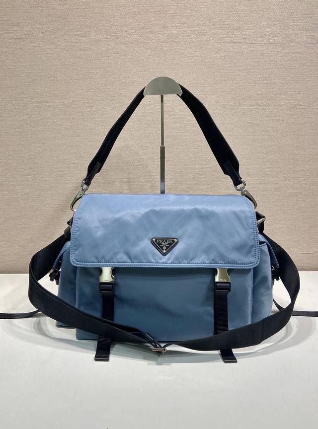 680新品邮包2Vd082航空兰 这款Explore手袋完美融合了高雅与功能性，拥有多口袋的柔和线条轮廓。翻盖设计，专为城市探索和户外冒险而设计，配有肩带和可拆