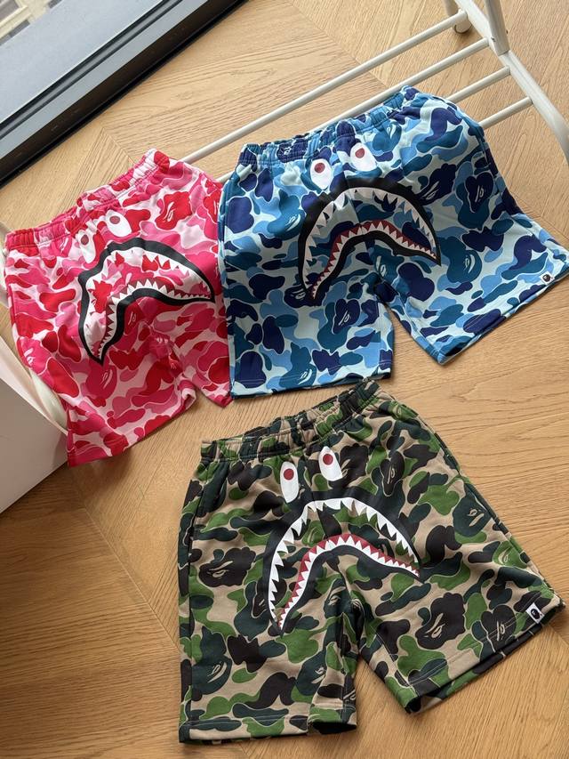 供120 Bape 26Ss经典 迷彩系列 鲨鱼短裤绿色 蓝色 粉红S-Xl采用定制迷彩毛圈面料，触感软糯亲肤，透气性能出众。裆部鲨鱼图案采用进口胶印工艺，牢固