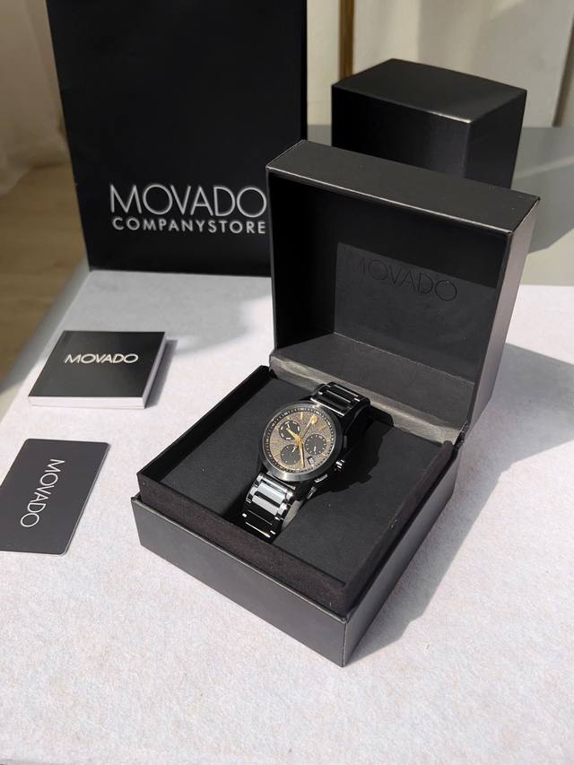 p910 Movado摩凡陀｜0607802博物馆运动计时腕表，承袭品牌经典博物馆圆点设计，12点位鎏金圆点镌刻百年品牌美学，极简黑金盘面跳出繁杂刻度束缚。43