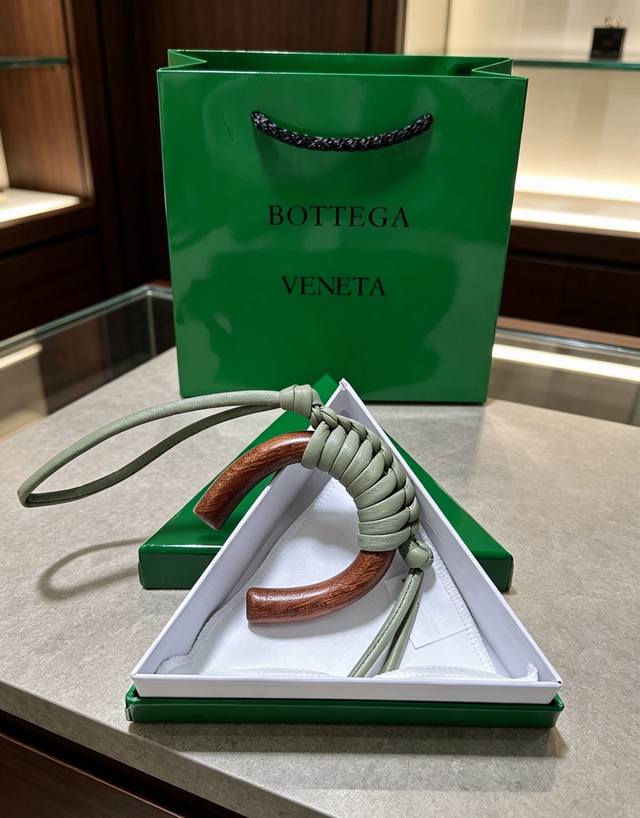 p90-Bottega Veneta 木编挂饰｜把意式极简揣进包里 温润胡桃木弧形轮廓，手工编织小羊皮肌理 柔和浅灰绿自带松弛氛围感 没有繁杂标识，低调的