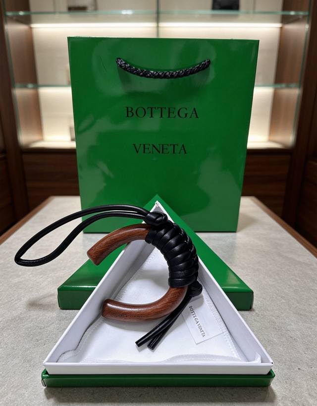p90-Bottega Veneta 木编挂饰｜把意式极简揣进包里 温润胡桃木弧形轮廓，手工编织小羊皮肌理 柔和耀黑自带松弛氛围感 没有繁杂标识，低调的质